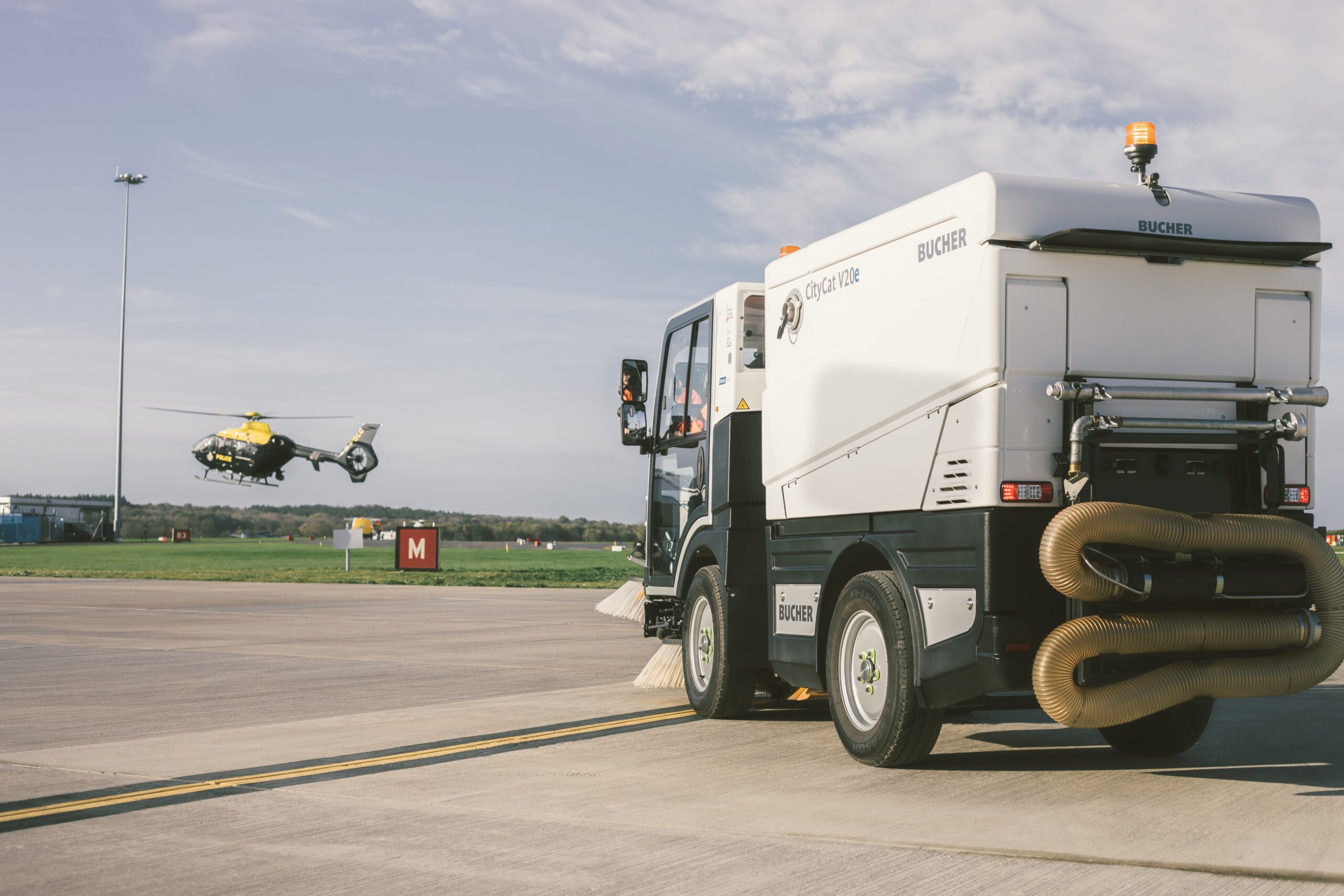 Bucher CityCat V20 compact sweeper operating on airport tarmac during active runway use