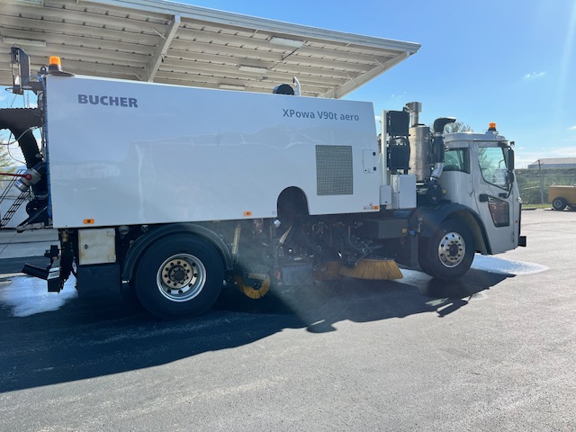 Bucher XPowa V90t Aero truck-mounted sweeper parked on pavement, showing side profile with sweeping brushes visible.