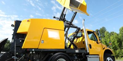 Bucher e35m street sweeper with raised yellow hopper during dump cycle